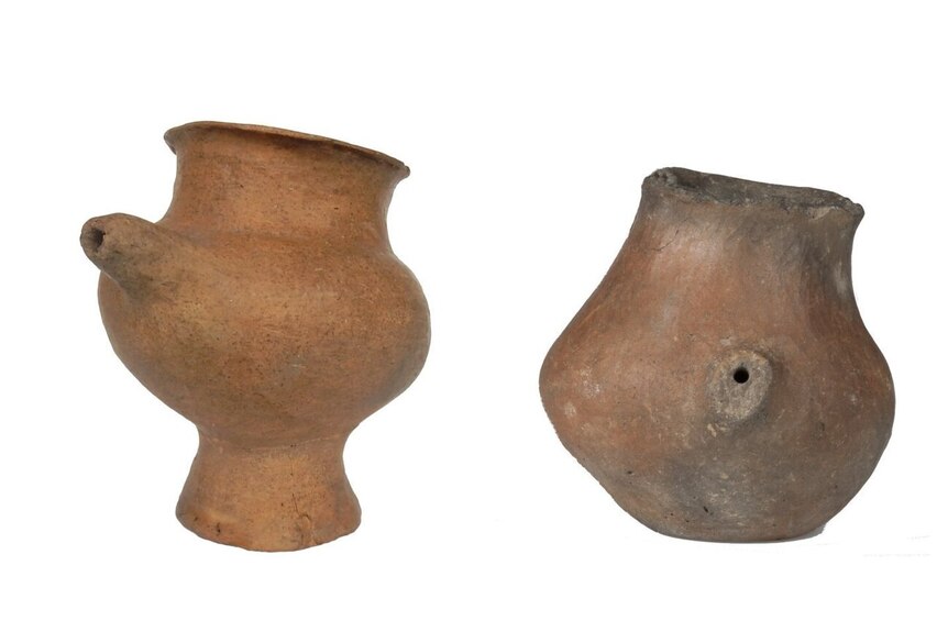 Four old spouted vessels are seen against a white background.