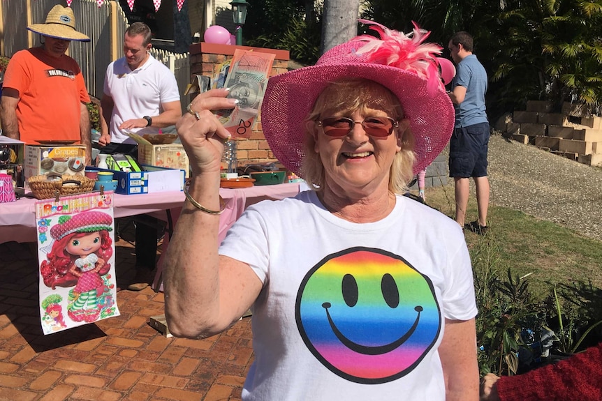 Carol Gould shows off money raised at a garage sale to benefit a neighbour