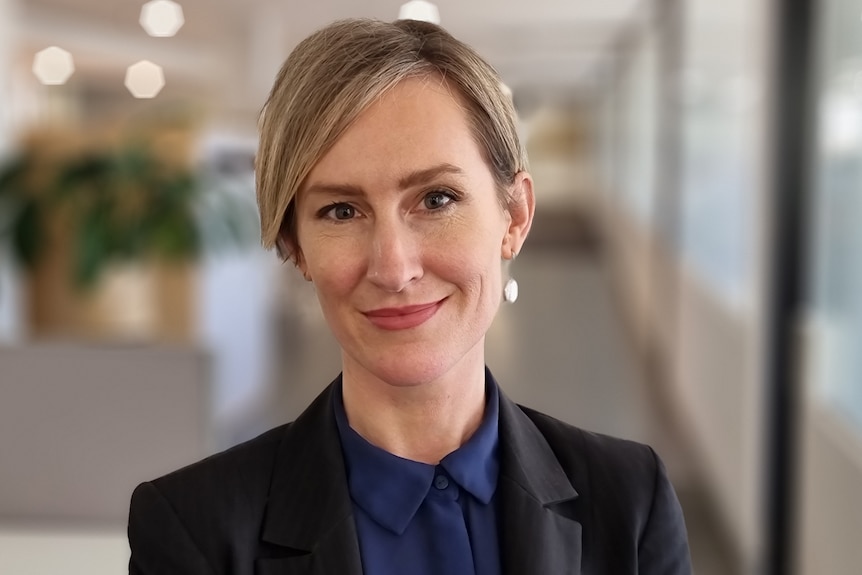 A woman wearing a black jacket over a blue shirt.