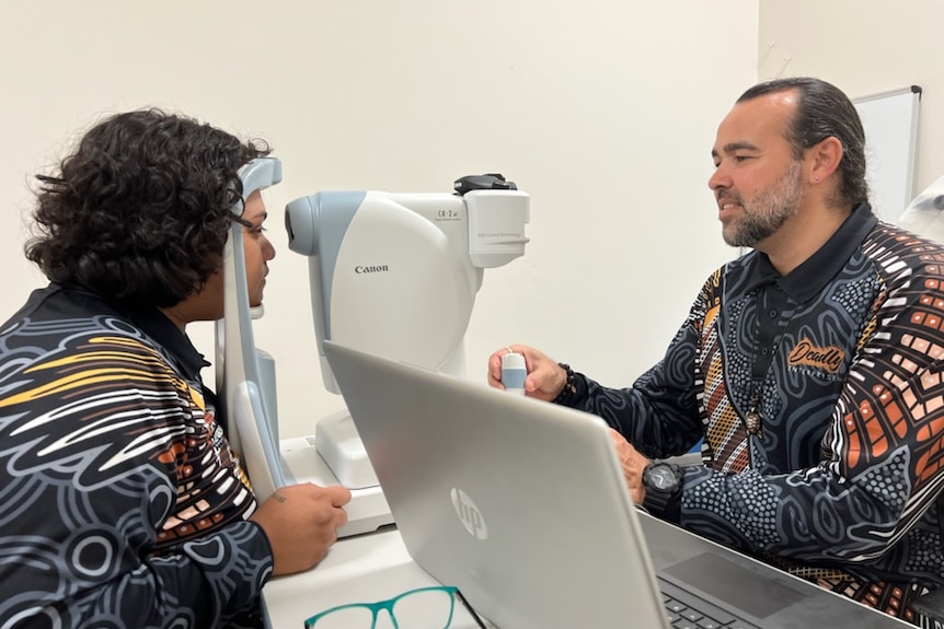 Two men, one taking an eye test and another supervising.