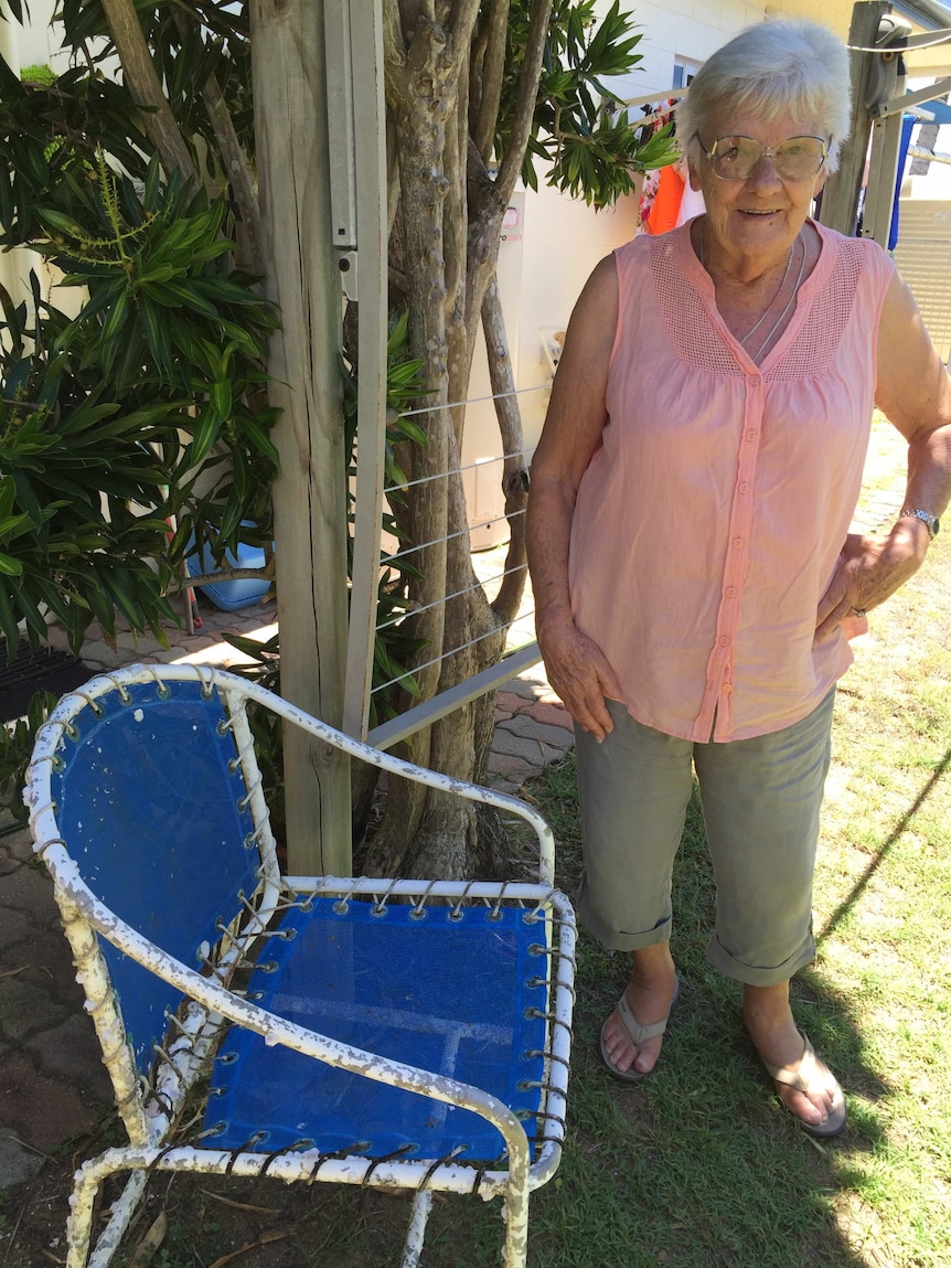 Woman stands beside chair covered in barnacles