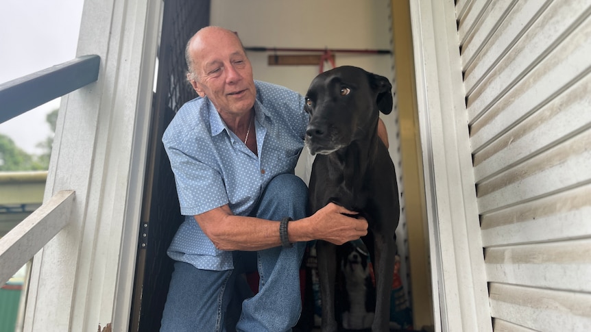 a man cuddles his dog in the doorway of his home