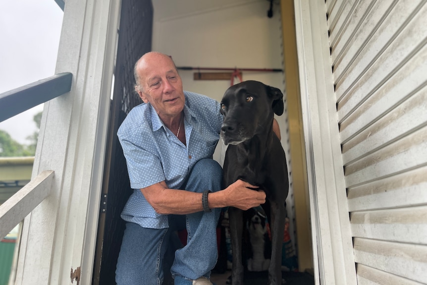 a man cuddles his dog in the doorway of his home