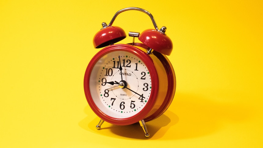 A red alarm clock on a yellow background. 