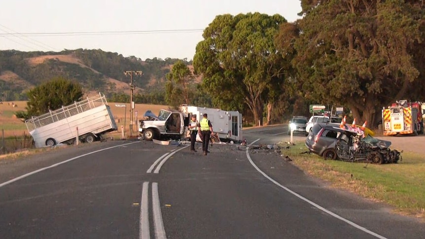 A truck towing a trailer and a station wagon damaged on road with police around