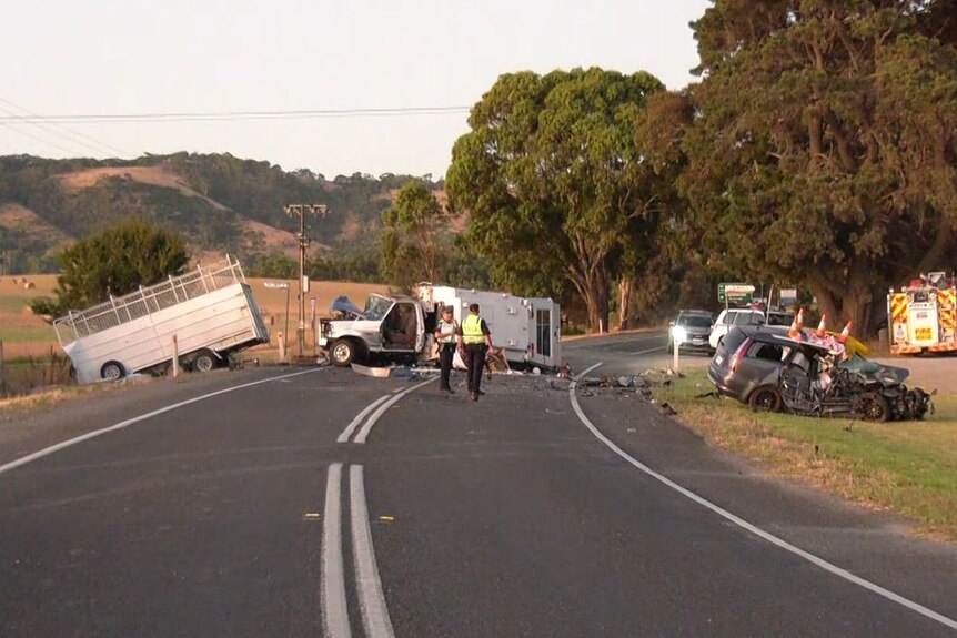 A truck towing a trailer and a station wagon damaged on road with police around
