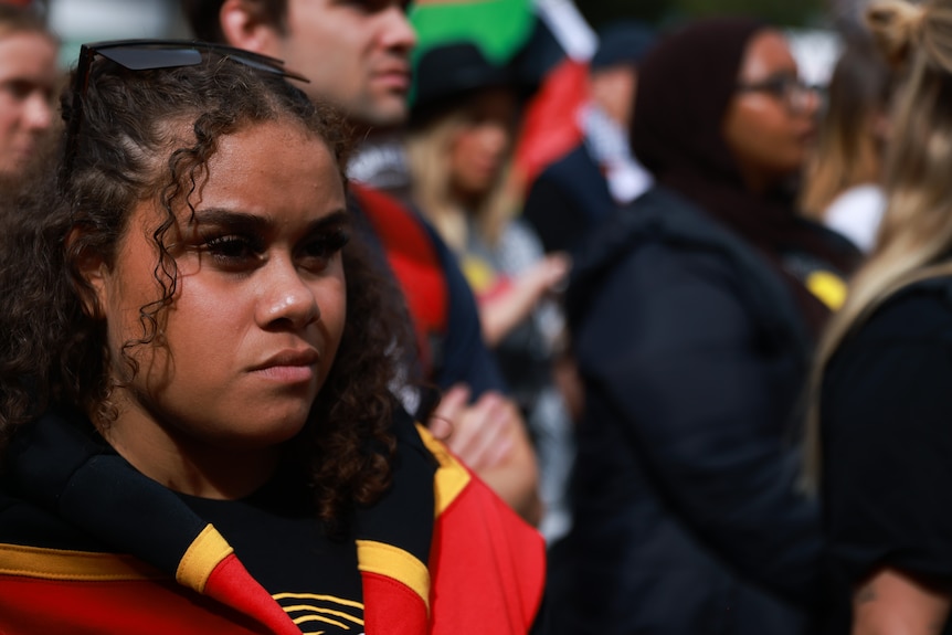 A protester dressed in the colours of the Aboriginal flag.