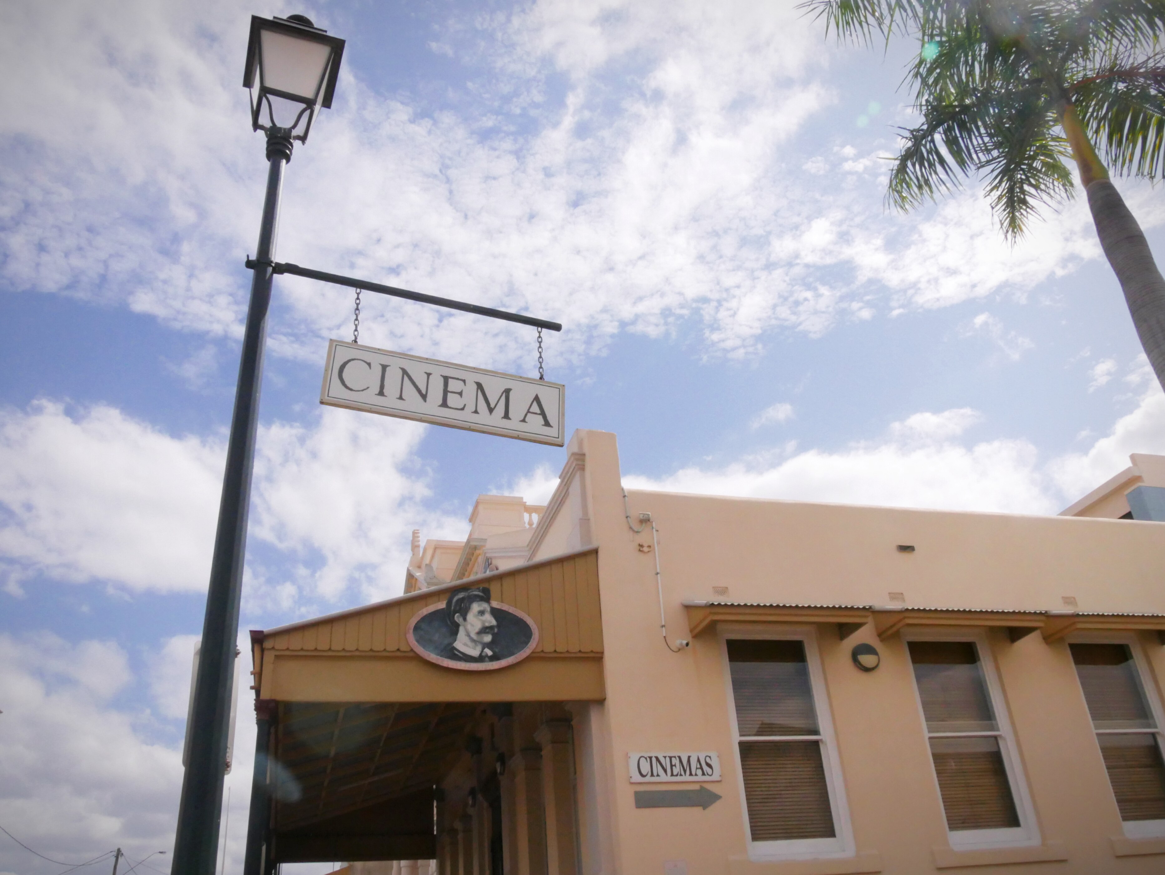 An old-fashioned cinema sign hanging from a lamp post.