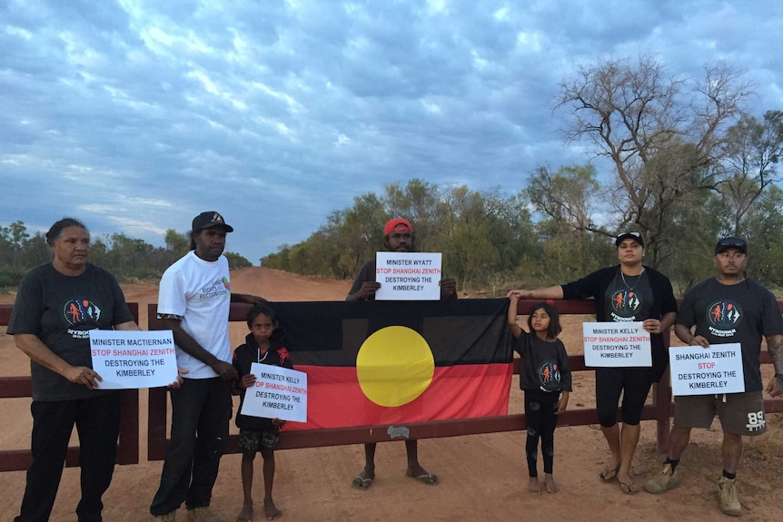 Image of a group of people standing on a road leading into an isolated bush property.