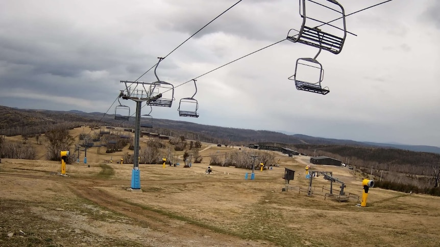 Two empty chair lifts float above brown grass at Mount Selwyn in Victoria