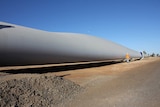 A wind turbine blade lying on the ground waiting to be installed.