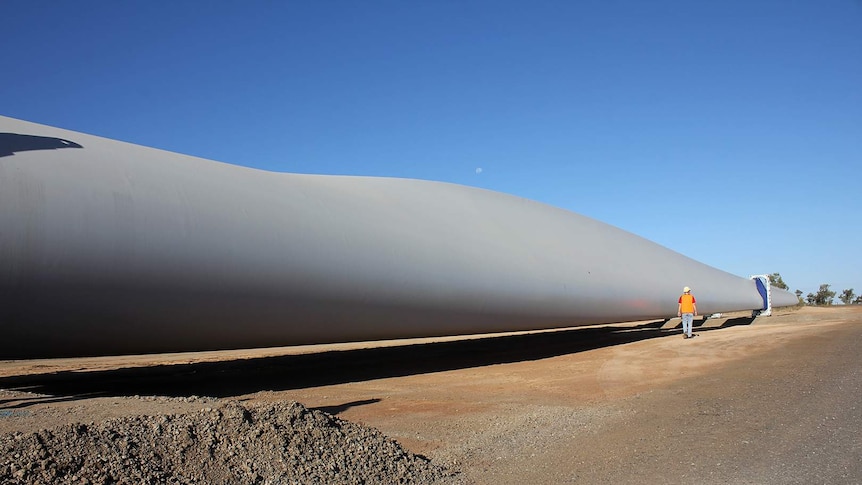 A wind turbine blade lying on the ground waiting to be installed.