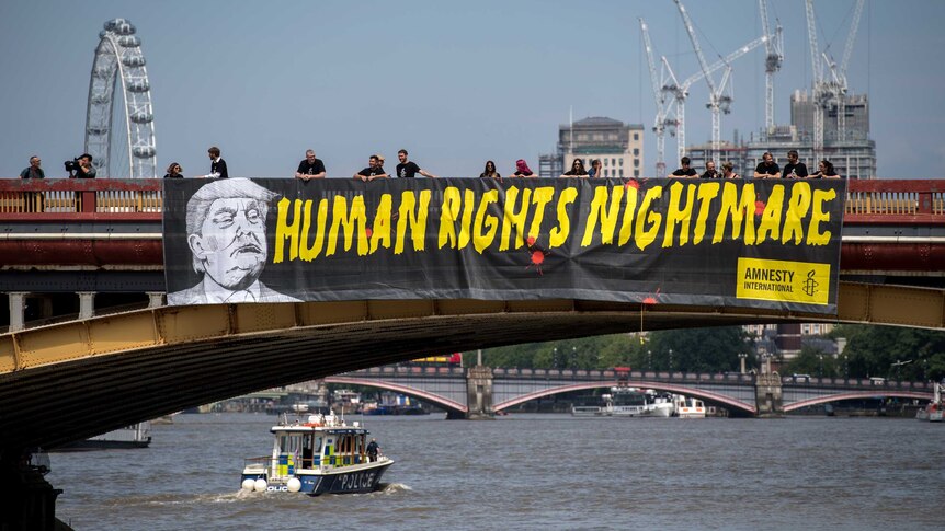 Amnesty International drops a banner with a picture of Donald Trump and the words "human rights nightmare".