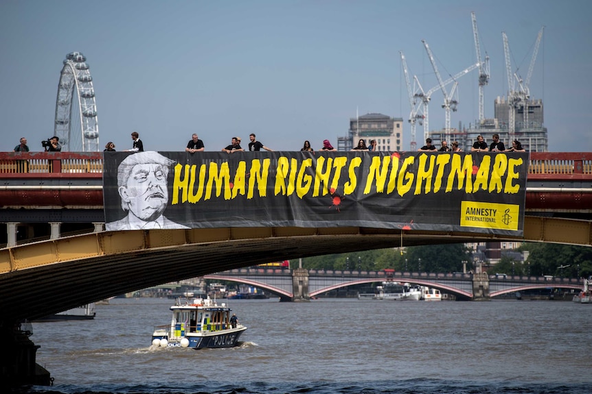 Amnesty International drops a banner with a picture of Donald Trump and the words "human rights nightmare".