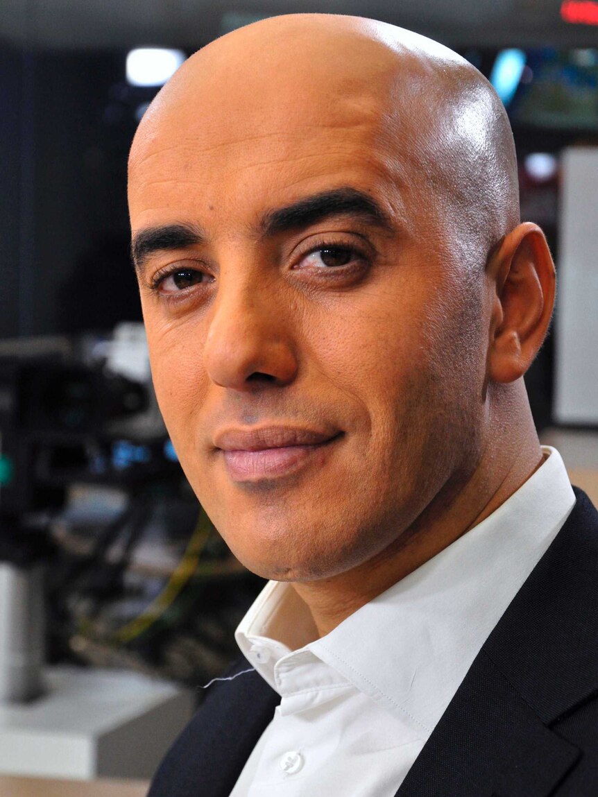 Close up of Redoine Faid wearing a white shirt and black suit jacket