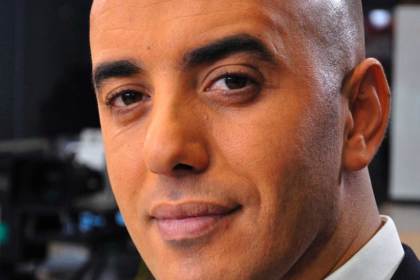 Close up of Redoine Faid wearing a white shirt and black suit jacket