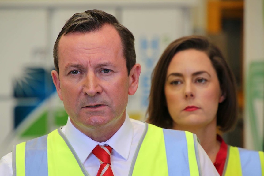 WA Premier Mark McGowan speaking at a media conference with a woman behind him.