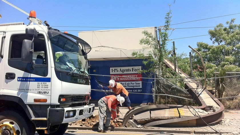 Workers deal with a fallen power pole and lines in South Road at Ridleyton.