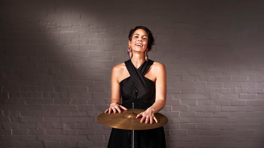 Percussionist Claire Edwardes stands with a cymbal on a stand.