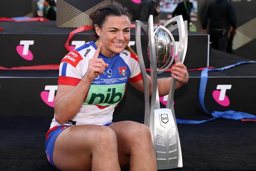 A woman celebrates with a rugby league premiership trophy 