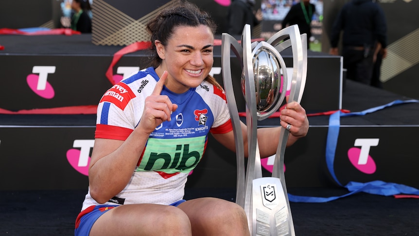A woman celebrates with a rugby league premiership trophy 