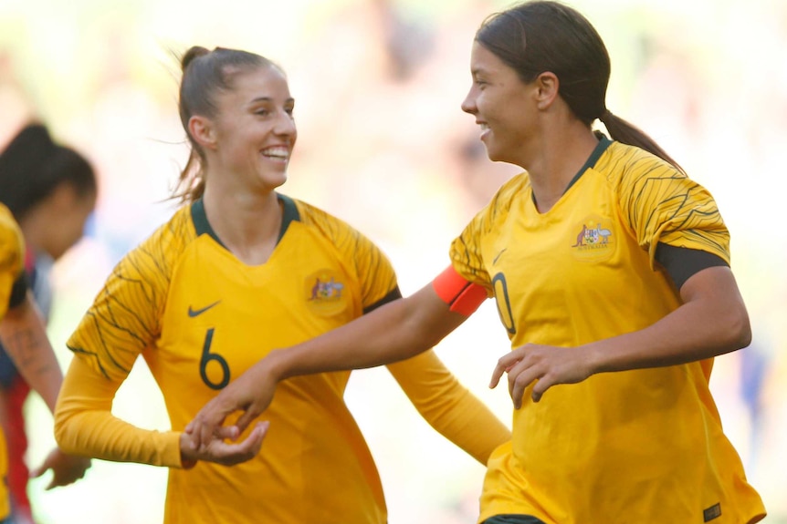Two of Sam Kerr's teammates run over to celebrate with her after another goal.
