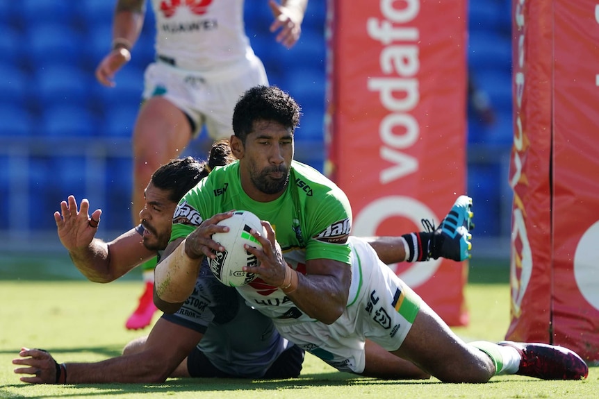 Iosia Soliola holds onto the ball with both hands and his eyes closed as he falls close to the ground