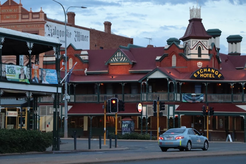 A large olden style building behind a traffic intersection. Another building hangs election campaign posters.