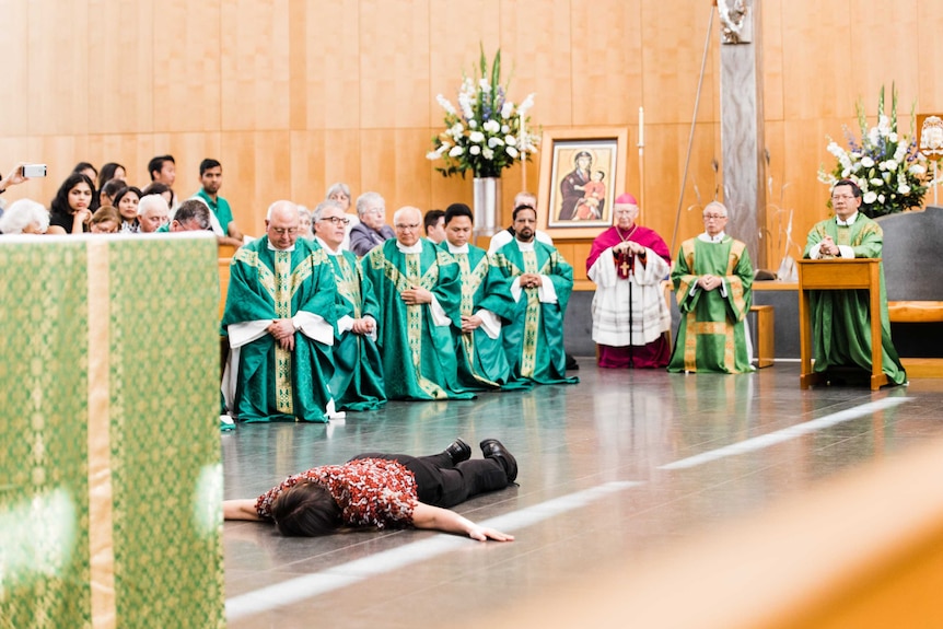 Zara Tai performing prostration, lying flat on the floor face down, during her consecration ceremony.