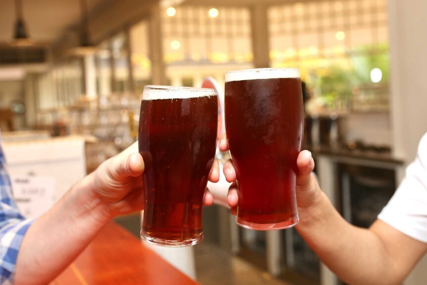 Two people clink pint glasses filled with a brown beer at the Windsor Hotel in Perth.
