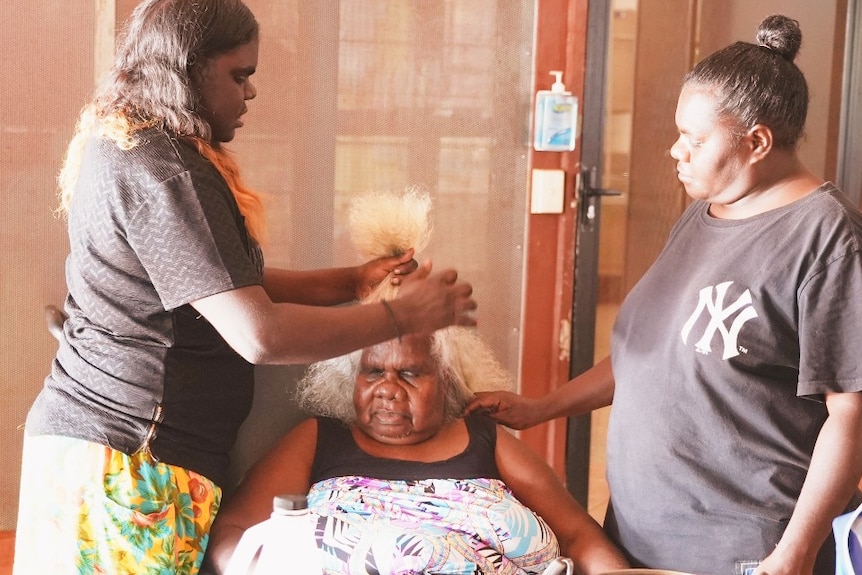 Two Aboriginal woman do the hair of an elderly Indigenous woman