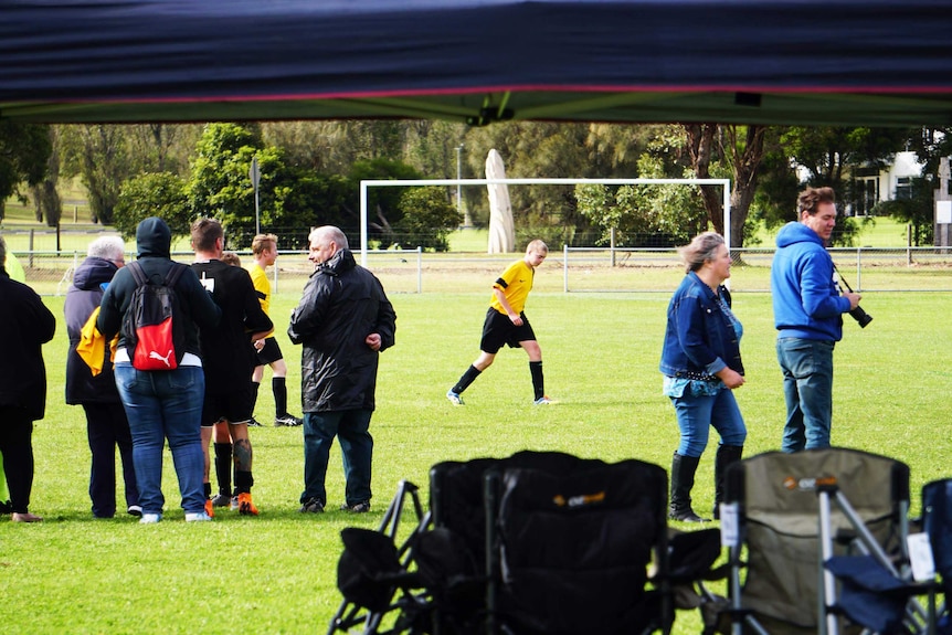 Parents and players huddle on a soccer pitch next to a marquee at the 2019 Limestone Cup in Mount Gambier.