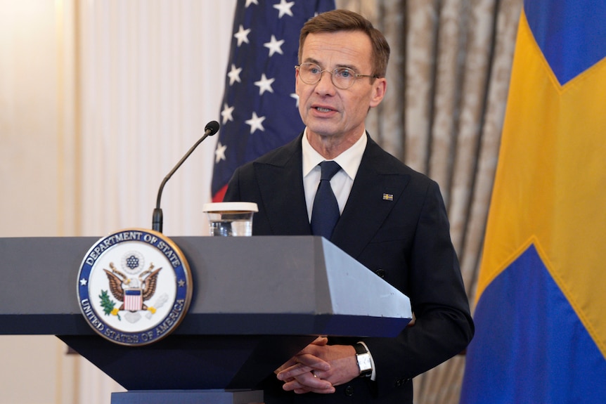 Prime Minister Ulf Kristersson standing at a podium with the US Department of State seal on it.