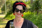 Ginger Gorman smiling and holding a glass of champagne in a story about how to set boundaries at Christmas