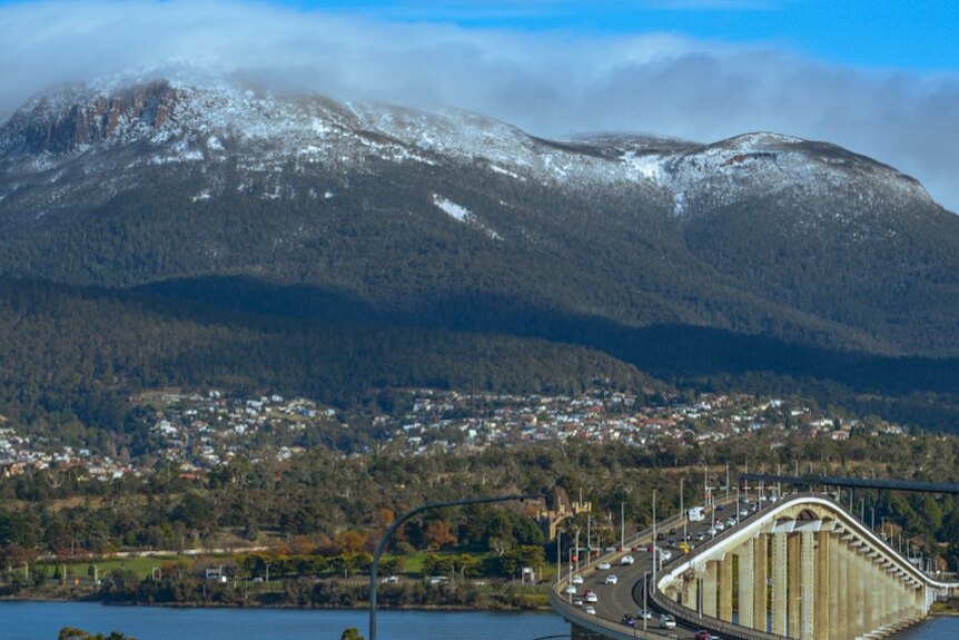 Snowy mountains looming above a busy bridge 