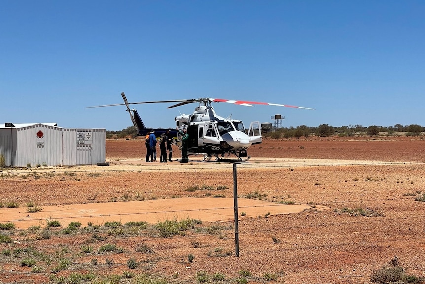 A helicopter and a shed in desert terrain