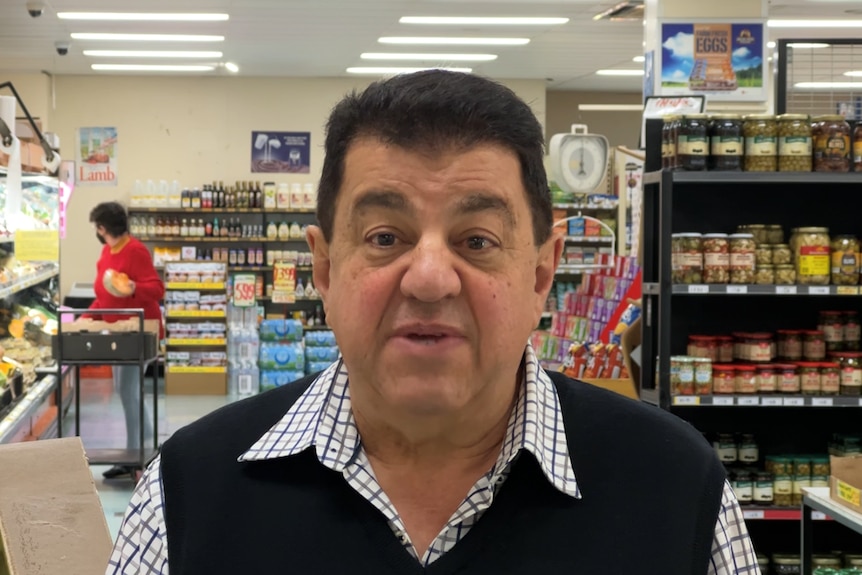 Man stars at camera with shopping shelves behind him