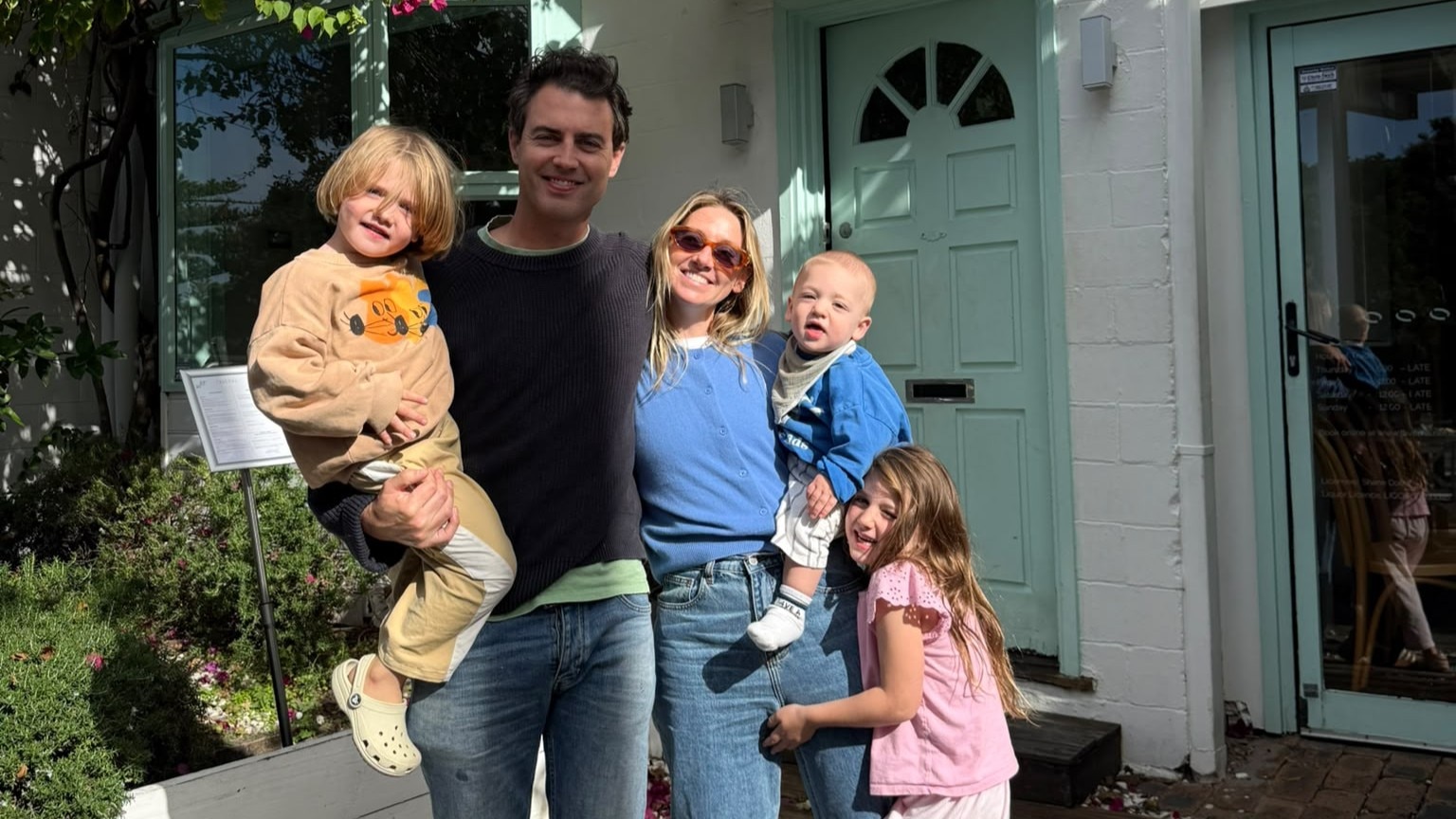 A family of five taking picture near a house
