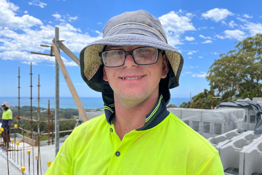 Lachie smiles at camera, wearing hi-vis at his construction site
