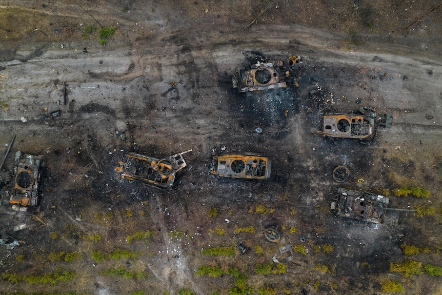 An aerial shot shows the wreckage of six burned out military vehicles.