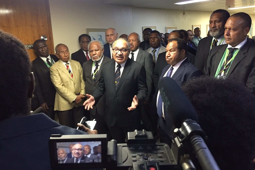 PNG Prime Minister Peter O'Neill stands surrounded by his party speaking to media.
