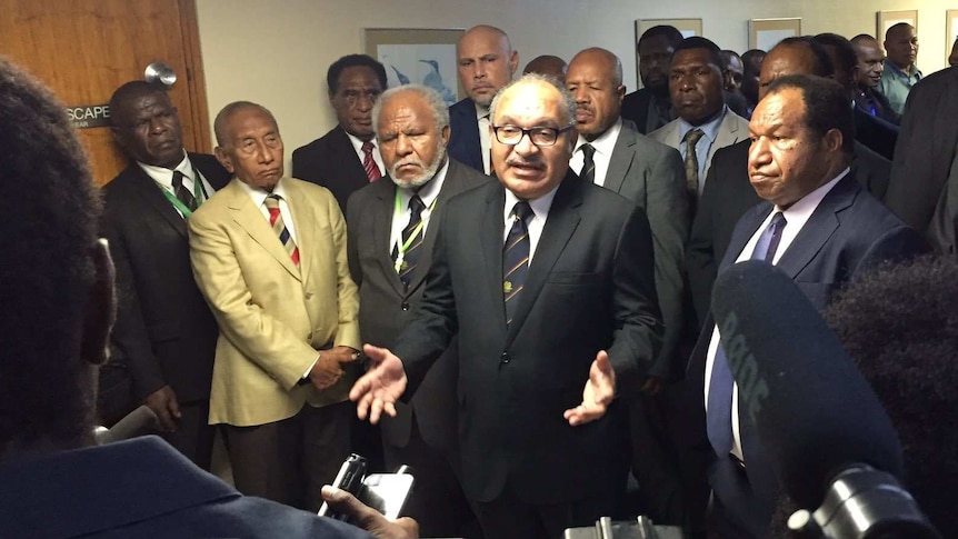 PNG Prime Minister Peter O'Neill stands surrounded by his party speaking to media.