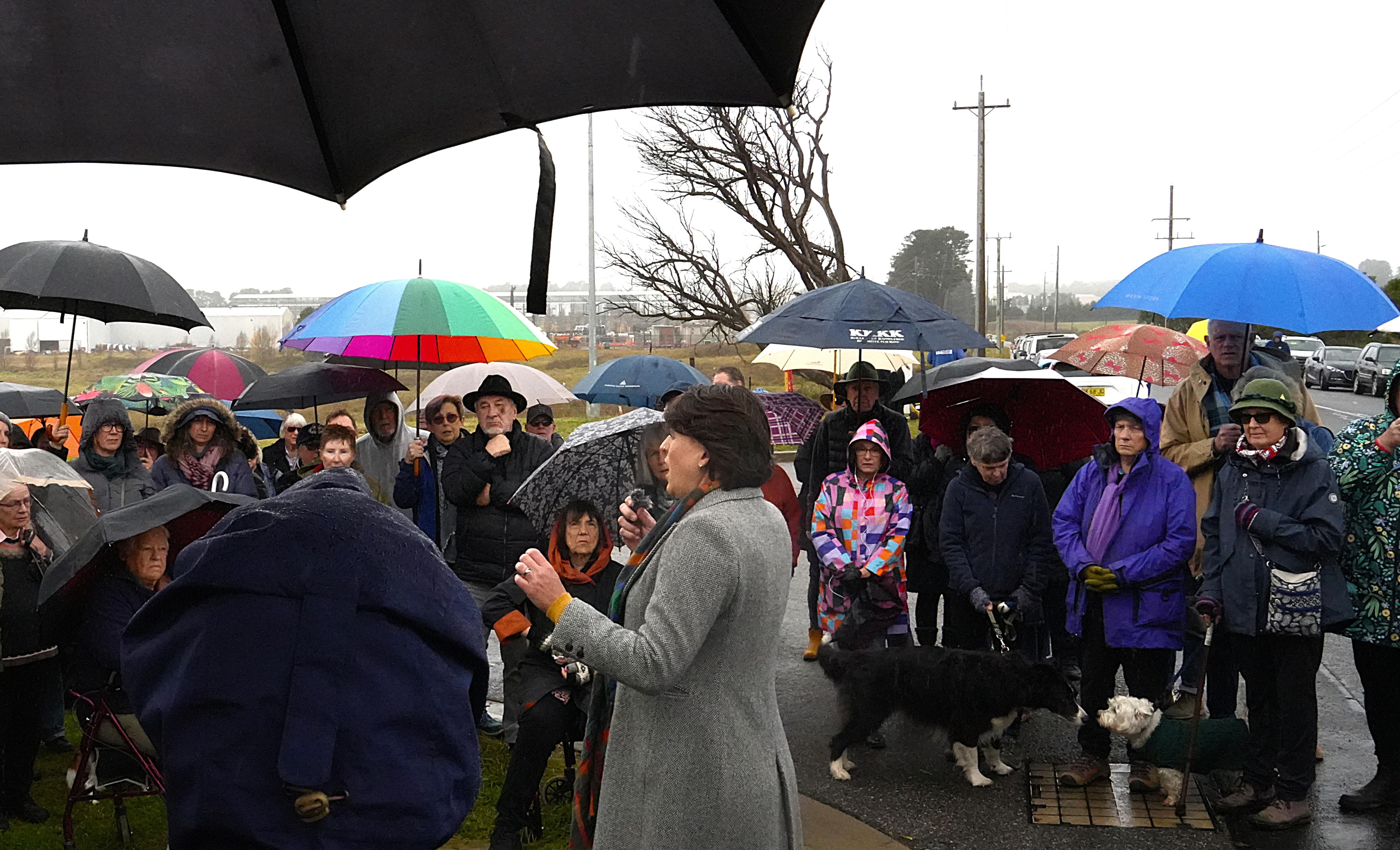 woman speaks to crowd in rain gear