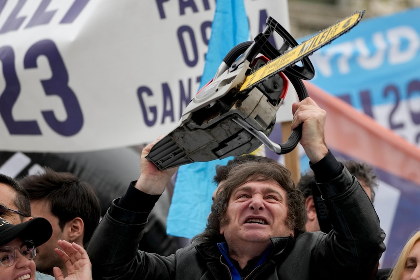 Javier Milei weilds a chainsaw above his head during a campaign rally.