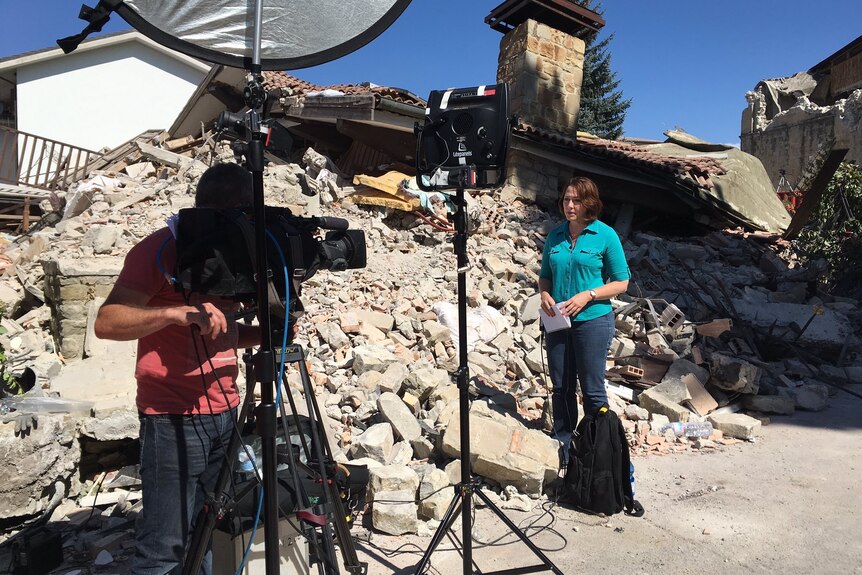 A camera crew surrounded by rubble.
