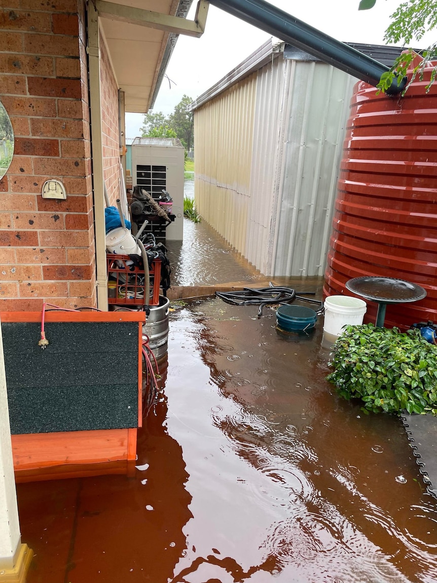 Floodwaters surround a single-storey brick house.