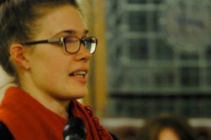 Courtney Landers holding a microphone in her hand and speaks at a public meeting.