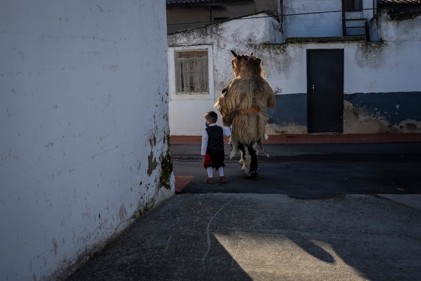 Un niño pasa junto a un hombre disfrazado de animal salvaje.