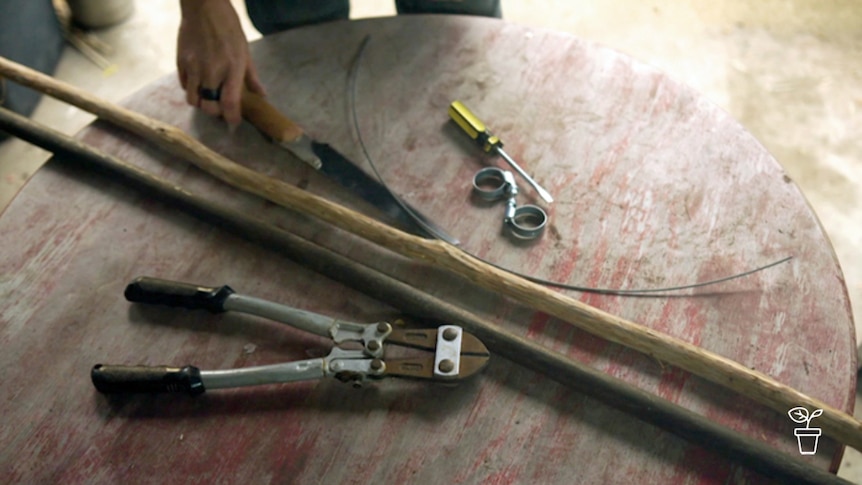 Table with hand tools and long wooden handles lying on it