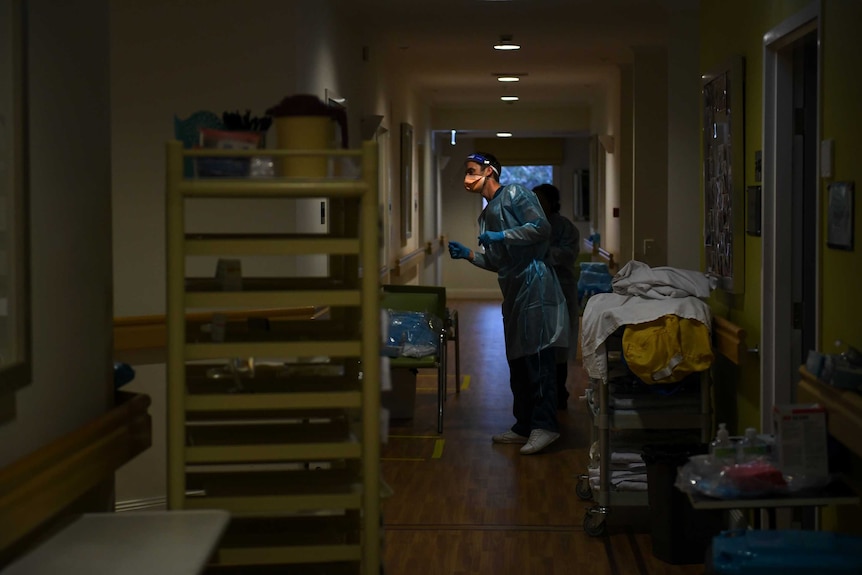 A man stands in a hallway looking through a doorway.